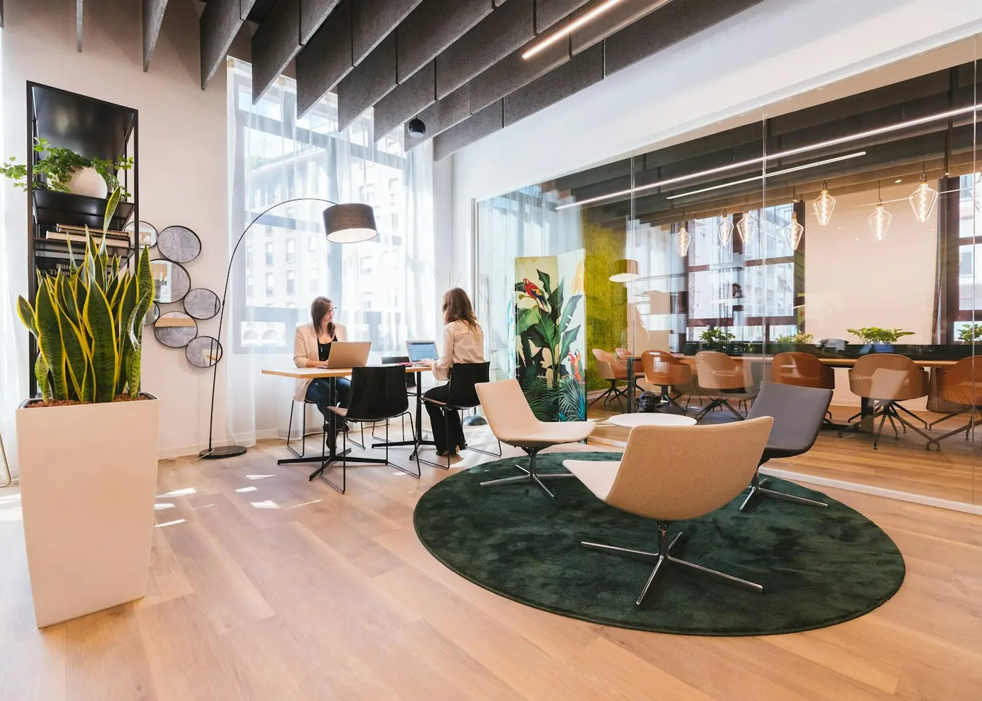 A bright flexible workspace with lounge chairs, shared desks and glass-walled meeting rooms