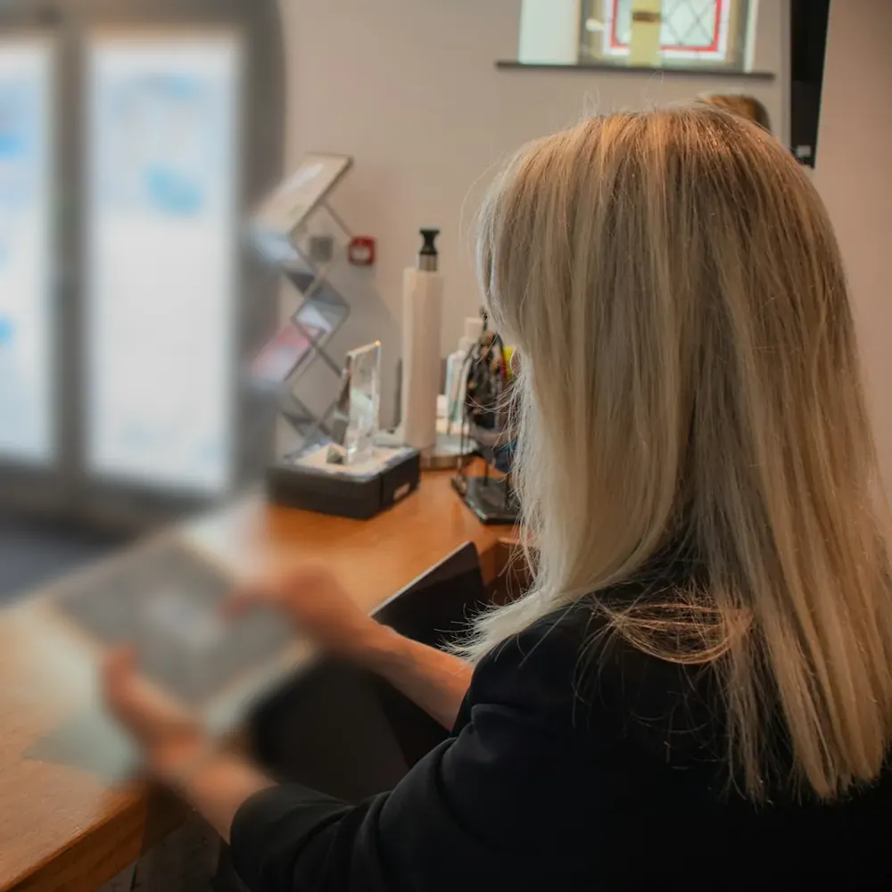 A receptionist using a tablet at a front desk
