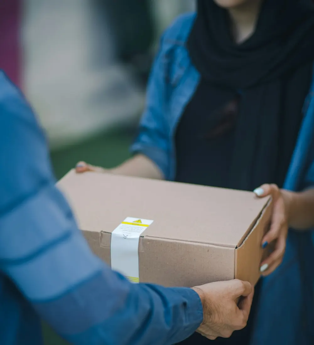 A parcel being handed over to a woman across a counter